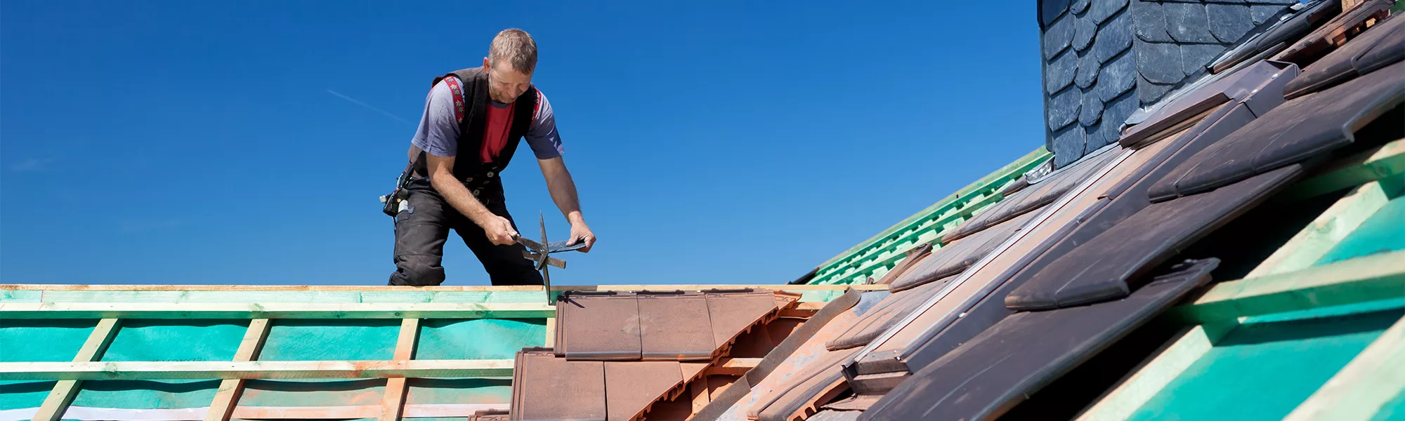 Roofer working with tools on residential roof